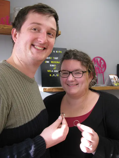 Katie and Brian holding the wedding rings they made at Orla James